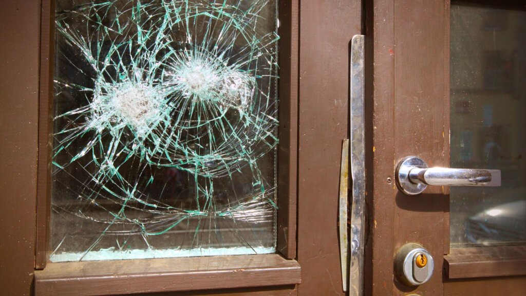 Vandalized front door with shattered glass