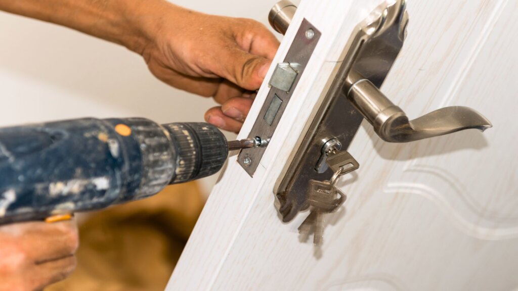 Person installing door lock with power drill