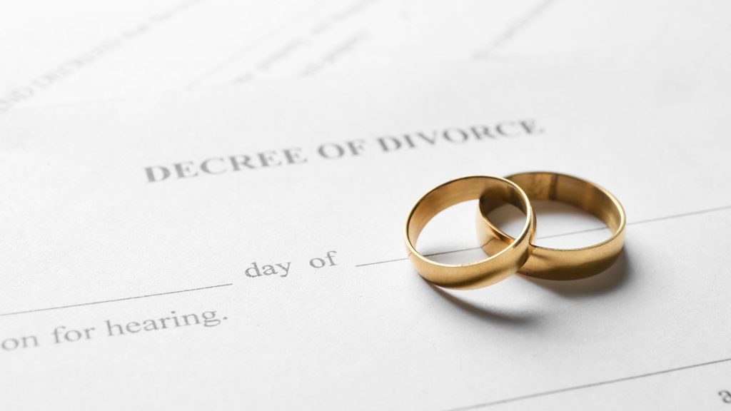 Wedding bands resting on a signed divorce decree