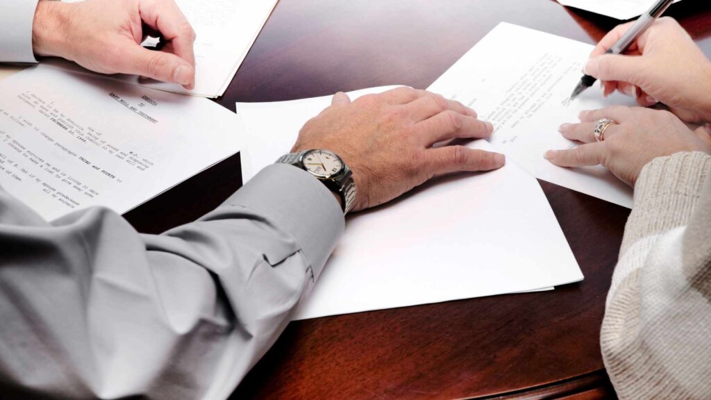 Two people reviewing and signing paperwork at desk