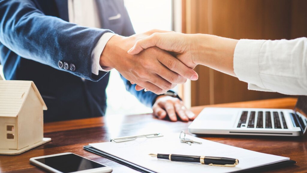 Home seller and buyer shaking hands after signing documents