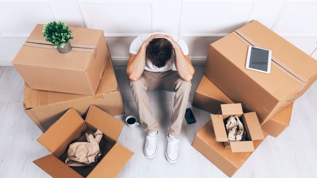 Stressed homeowner sitting on the floor surrounded by moving boxes
