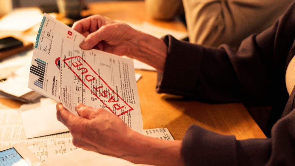 Person holding a past due bill with red overdue stamp