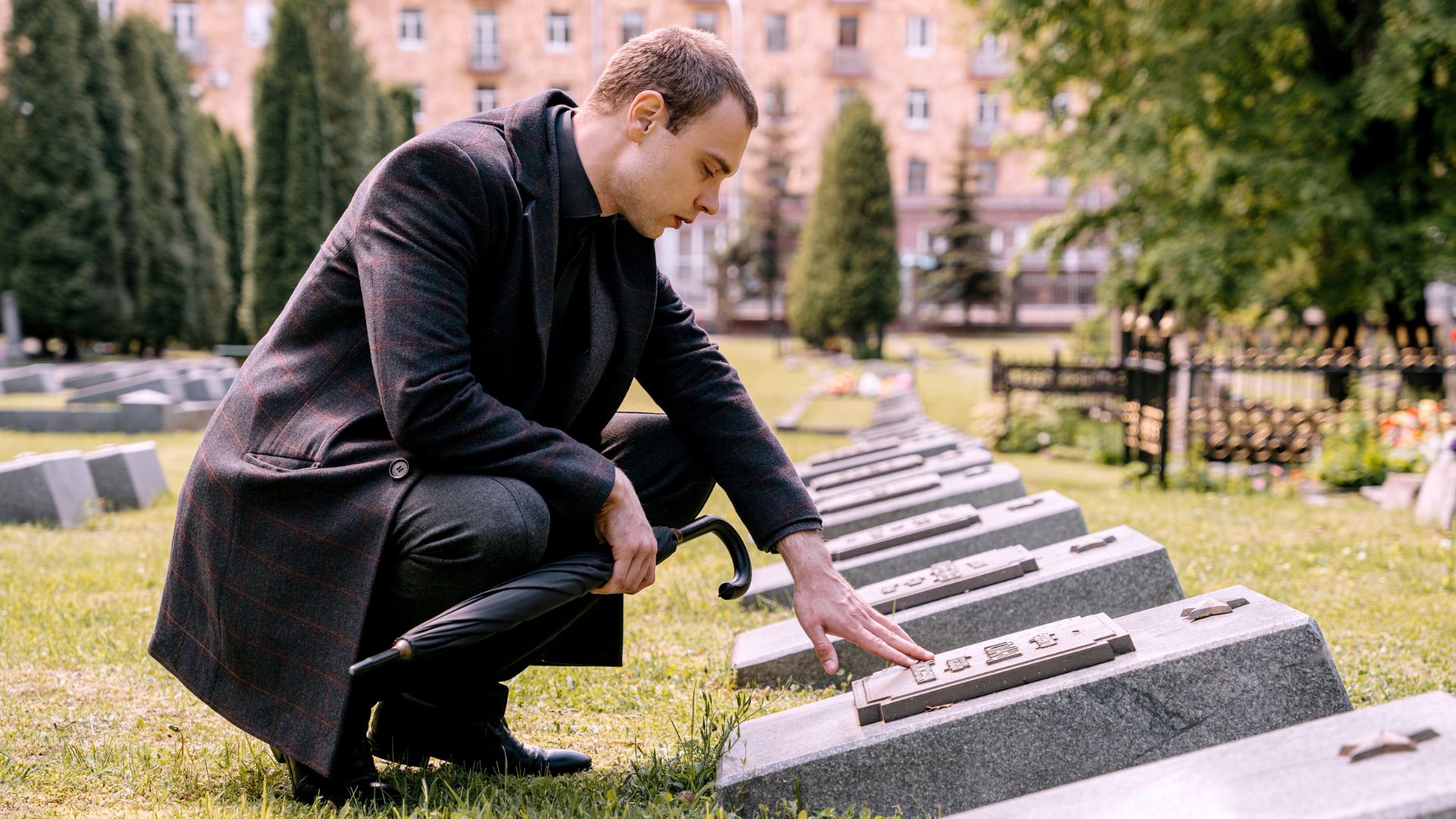 Man kneeling and touching gravestone in cemetery