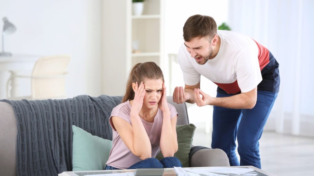 Man arguing with woman seated on couch