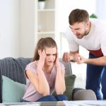 Man arguing with woman seated on couch