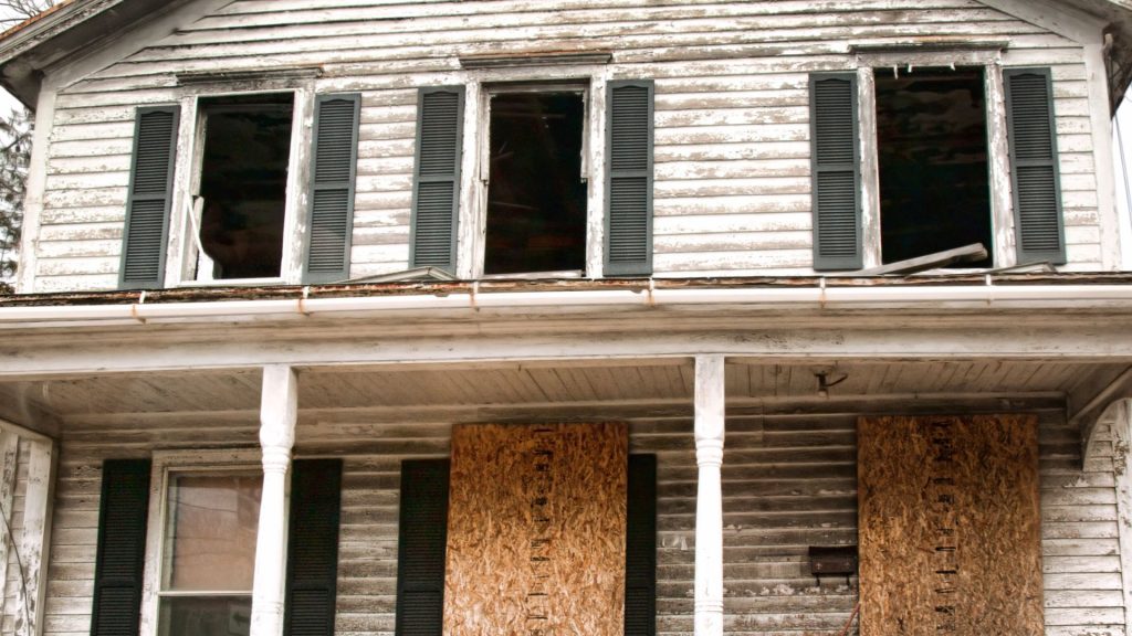 Boarded up vacant house with broken windows