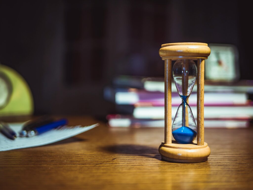 Hourglass with blue sand on a wooden desk