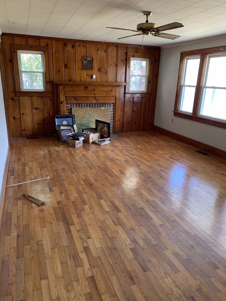 Empty living room with hardwood floors and wood paneled walls