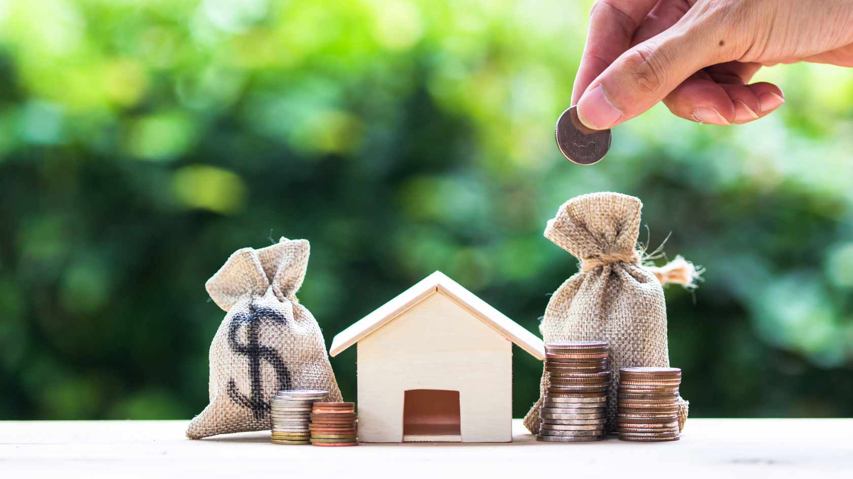 House model with coins and money bags representing dividing home sale proceeds