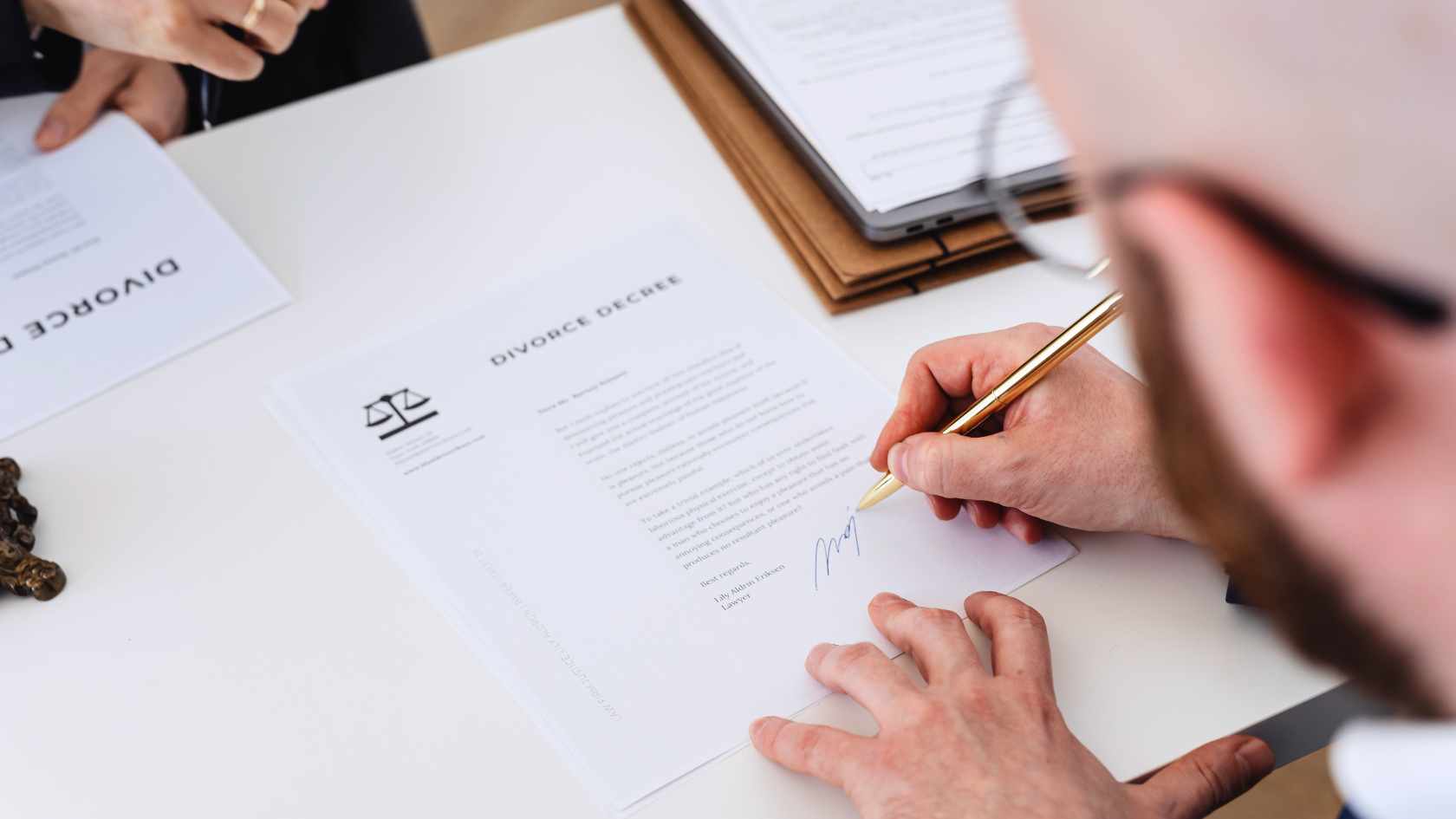 Person signing divorce decree paperwork during a legal process
